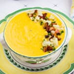 A bowl of Sweet Potato & Cauliflower Soup is sitting on a plate.