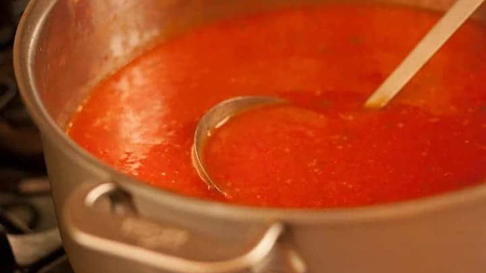 A pot of tomato soup with a ladle.