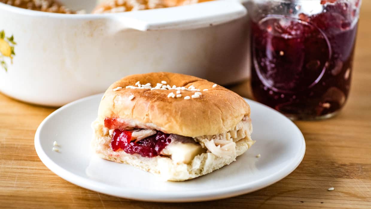 Cranberry turkey sliders on a plate next to a jar of cranberry sauce.