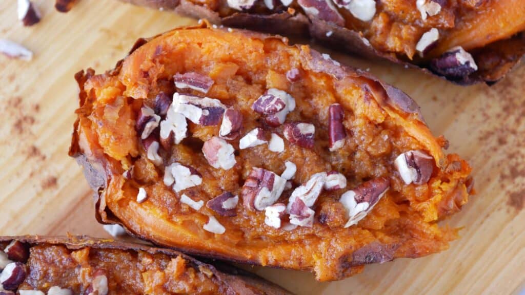 Sweet potatoes with pecans and nuts on a cutting board.