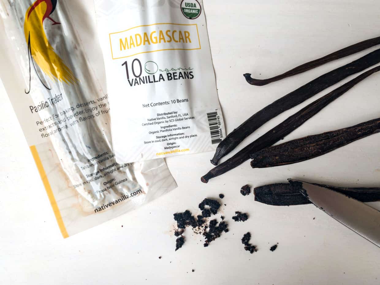 Packages of vanilla beans and a knife on a table.