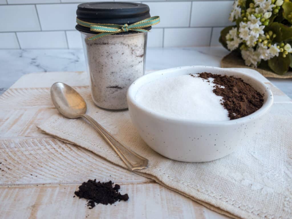 A bowl of sugar and vanilla powder and a spoon on a cutting board.