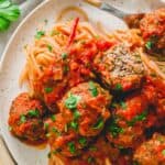 Venison meatballs in tomato sauce on a plate with pasta.