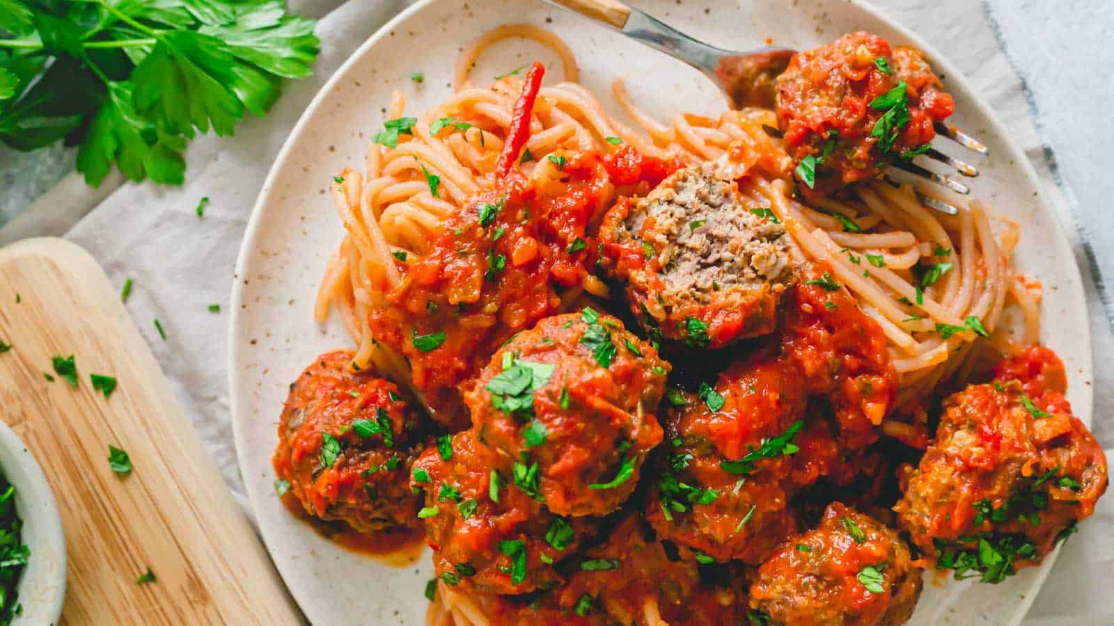Venison meatballs in tomato sauce on a plate with pasta.