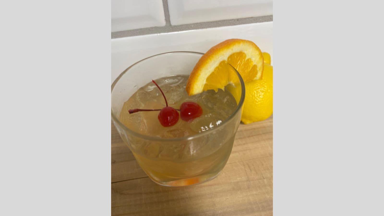 A drink with an orange slice and cherry on top.