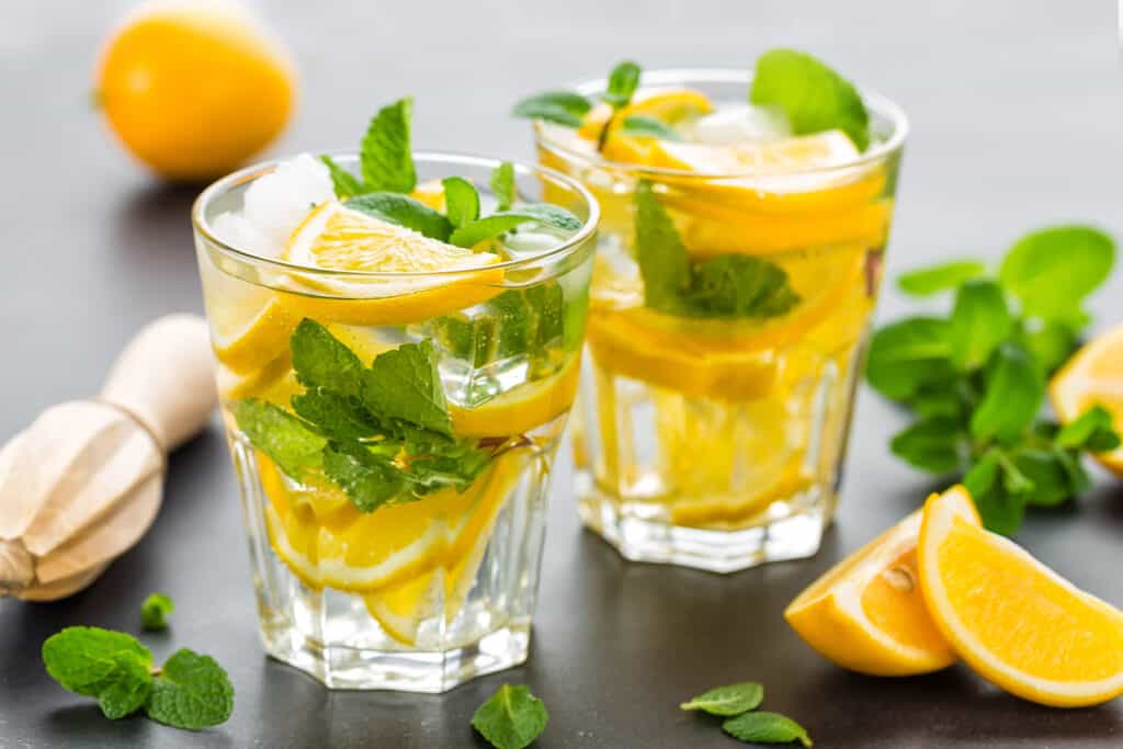 Two glasses of mocktails with lemon slices and mint leaves.
