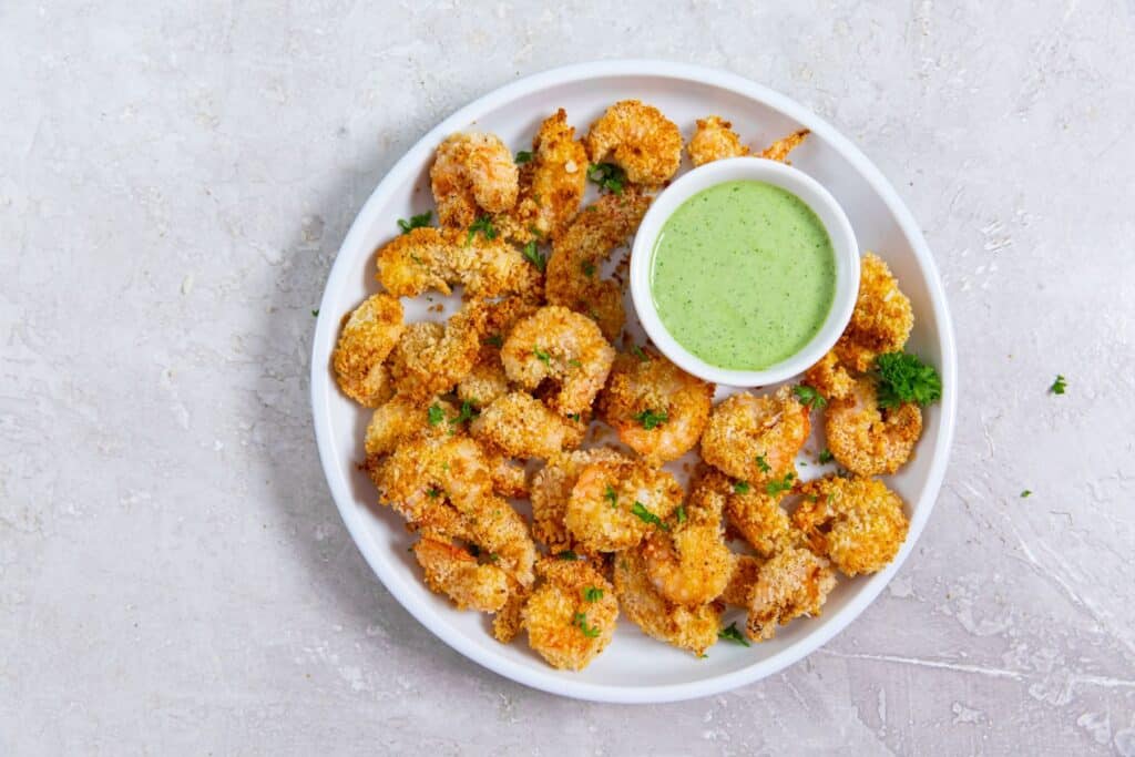 Fried shrimp with green sauce on a white plate.