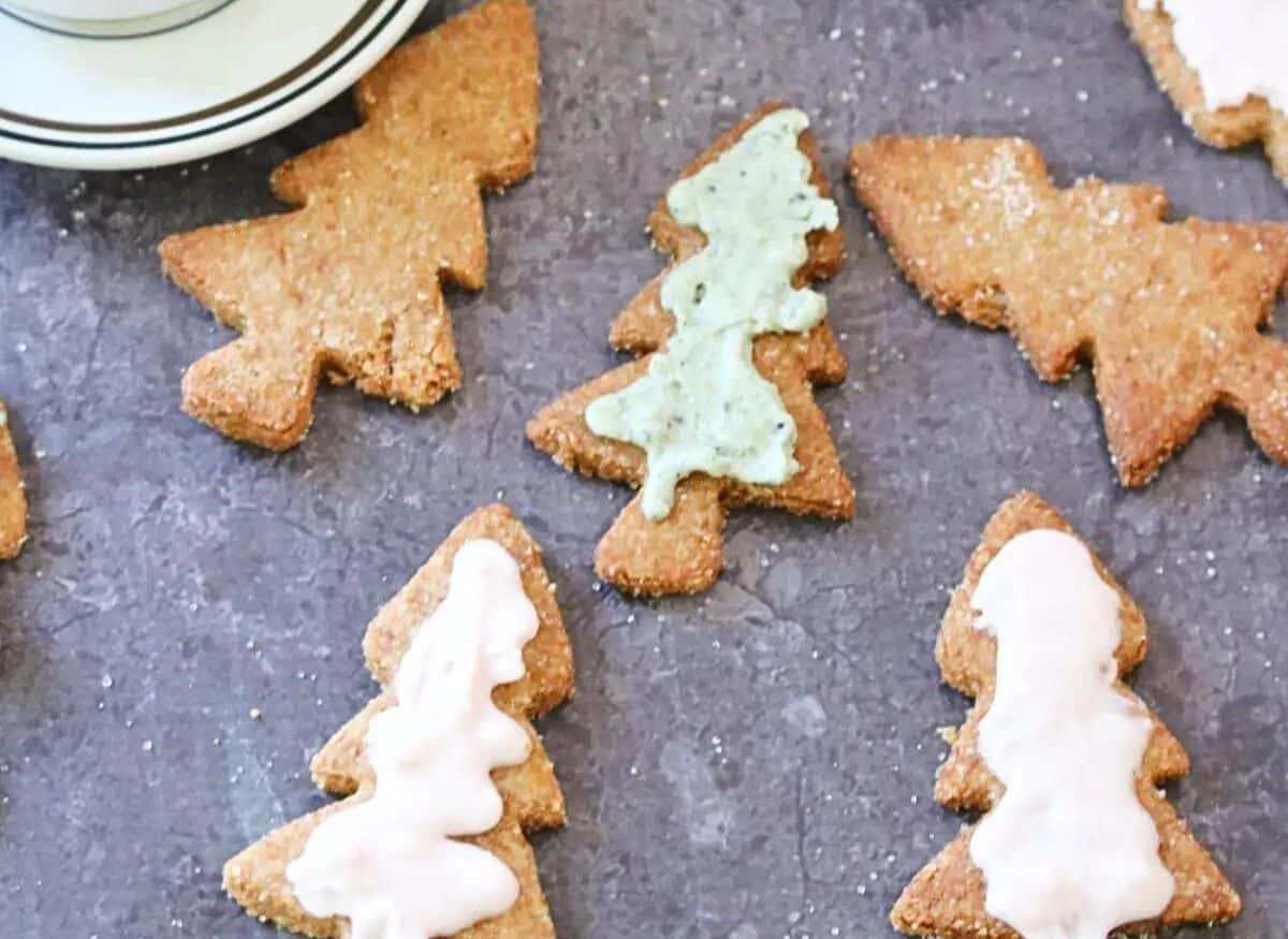 Almond flour sugar cookies in Christmas tree shape dusted with cane sugar around a cut of coffee.