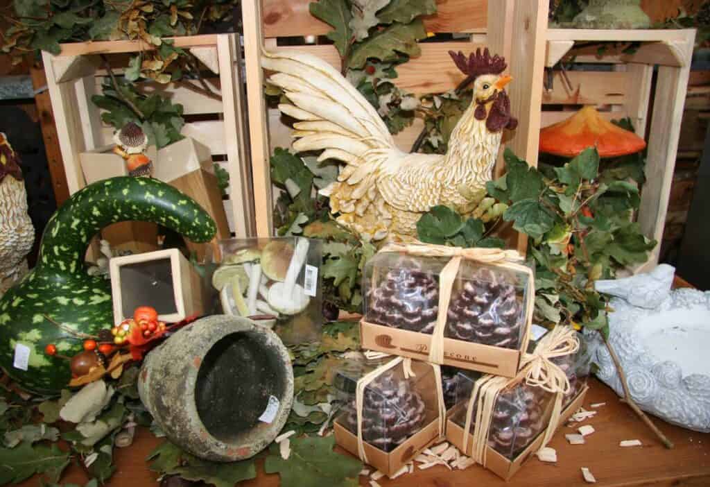 A rooster, pine cones, and other decorations on a table.