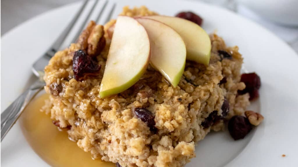 Oatmeal with apples and cranberries on a white plate.