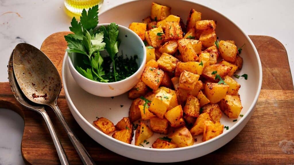 Breakfast potatoes with parsley on a wooden cutting board.