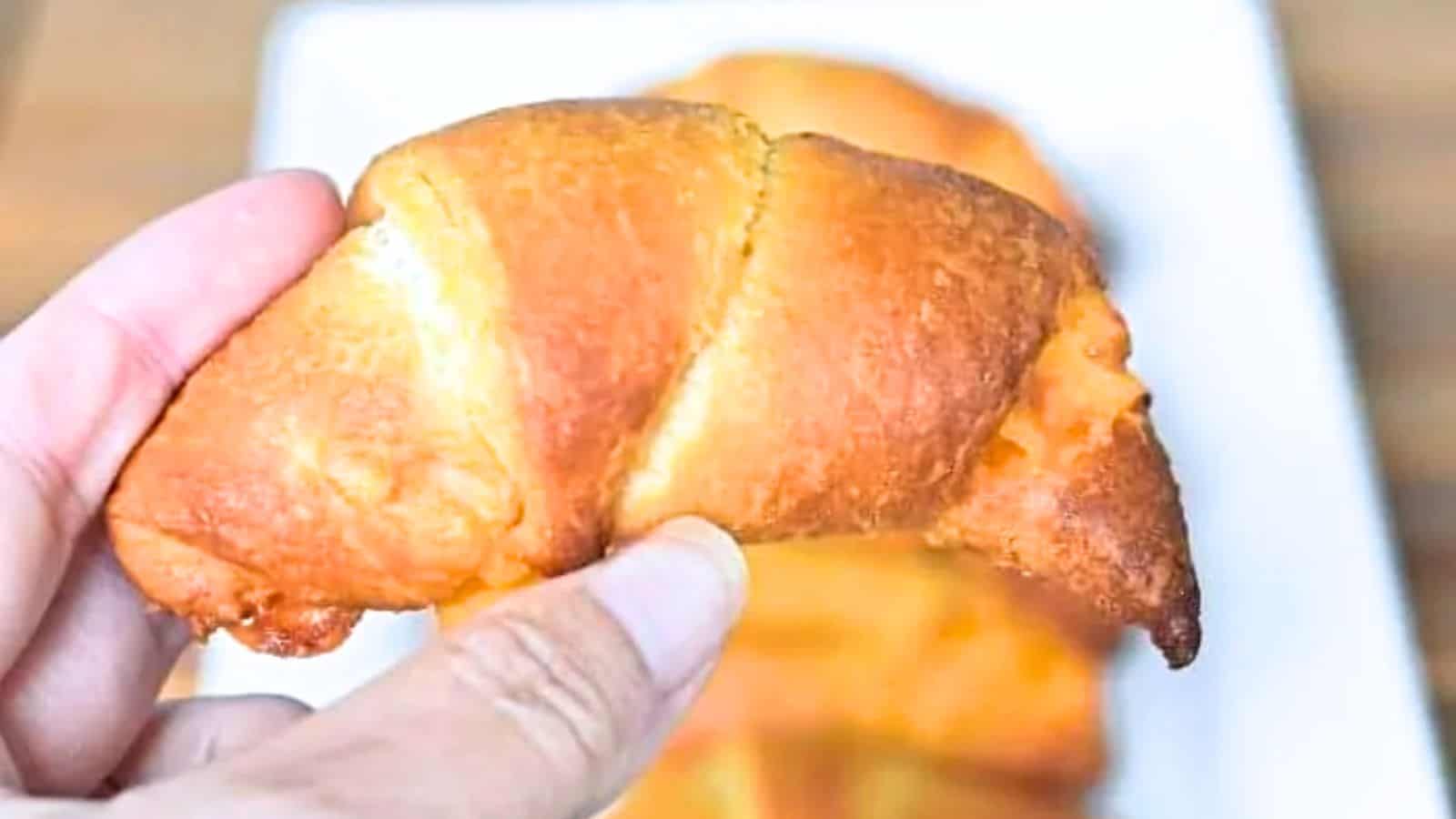 Image shows A person holding a buffalo chicken roll over a plate filled with more.