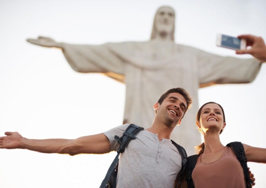 A couple participating in a scavenger hunt takes a picture of the Christ the Redeemer statue in Rio de Janeiro.