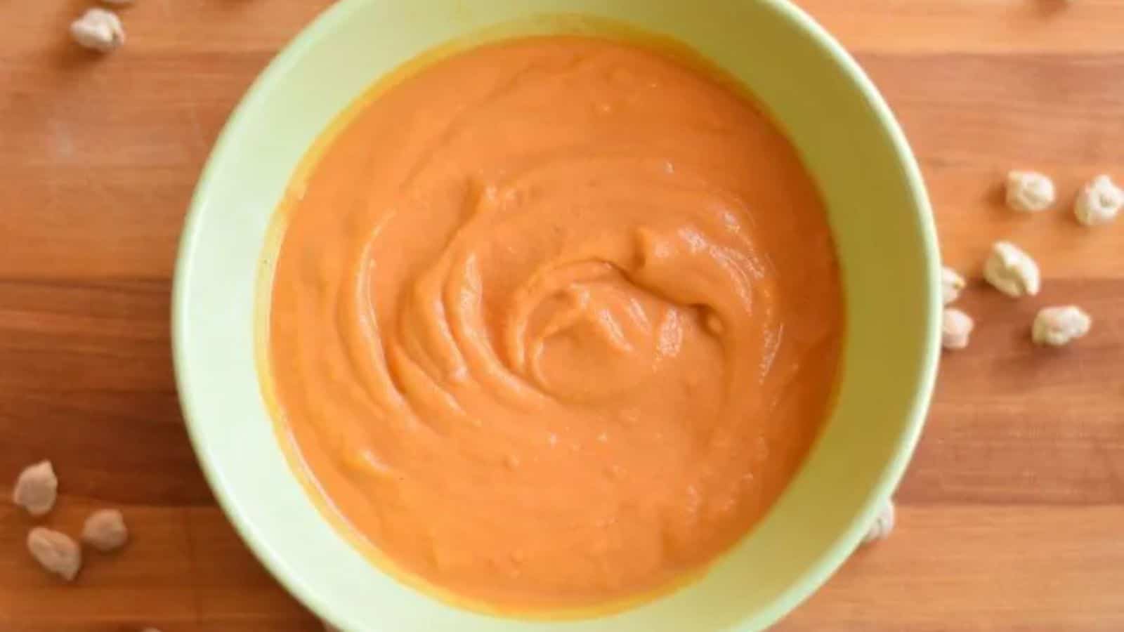 Image shows A bowl of creamy chickpea tomato soup with dried chickpeas around it.
