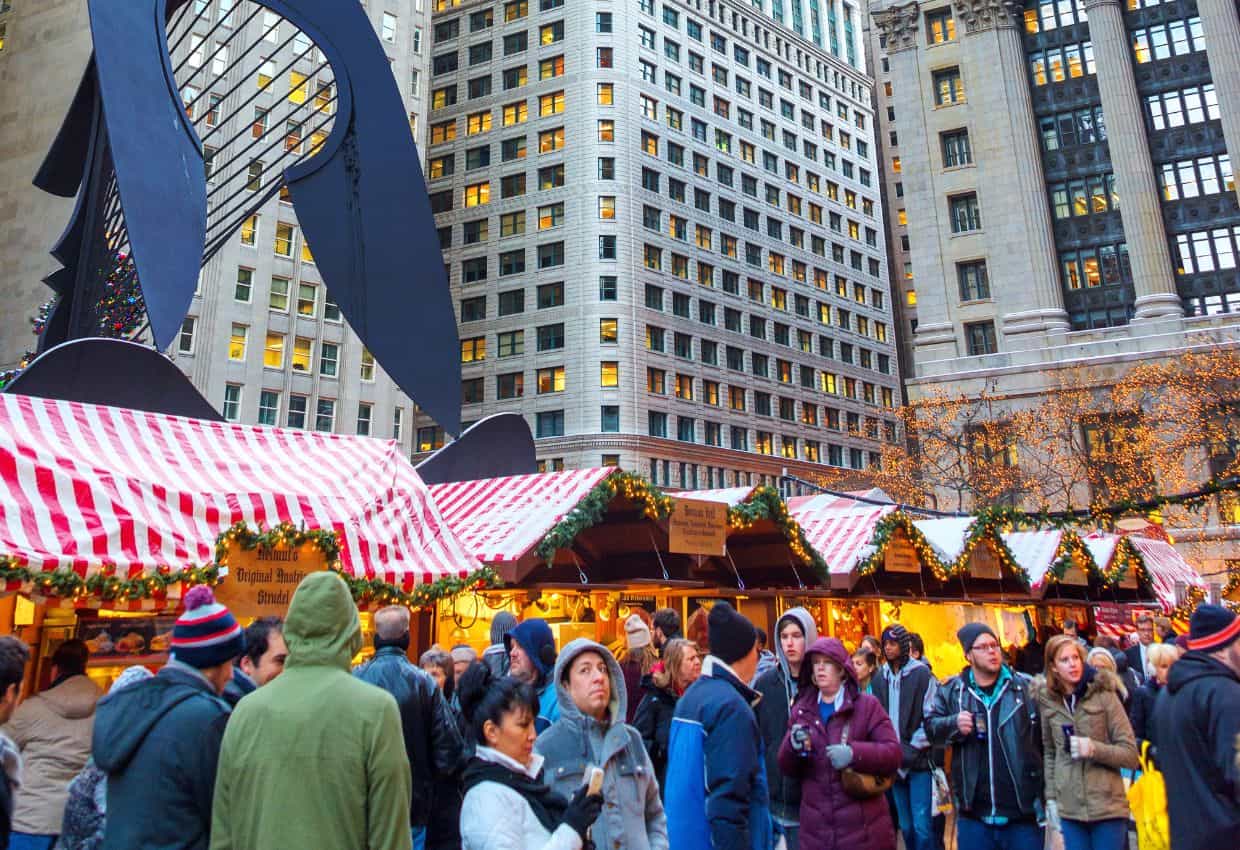 Image shows A festive gathering of visitors at the Christkindlmarket in Chicago.