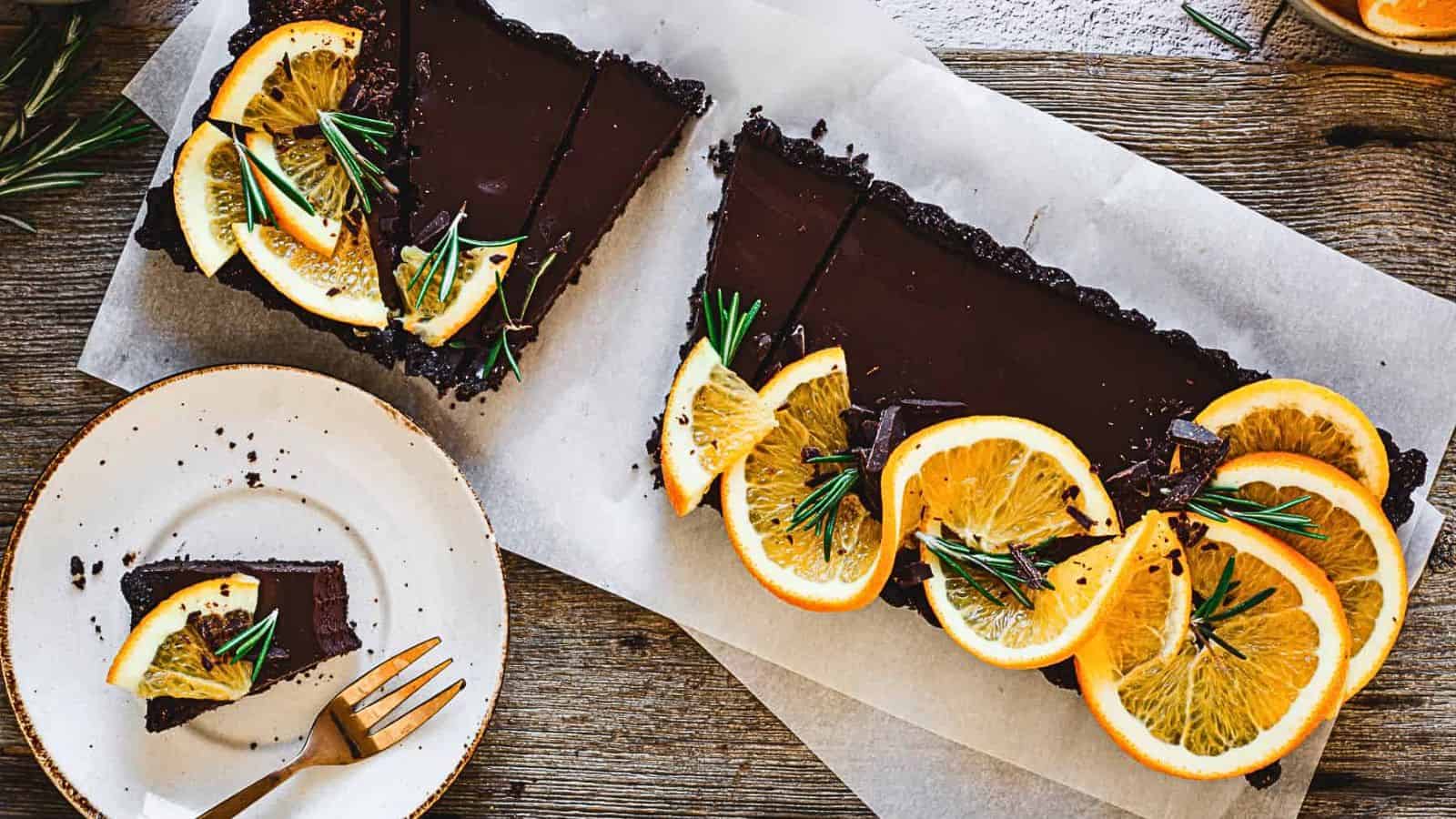 A chocolate tart with orange slices and rosemary.