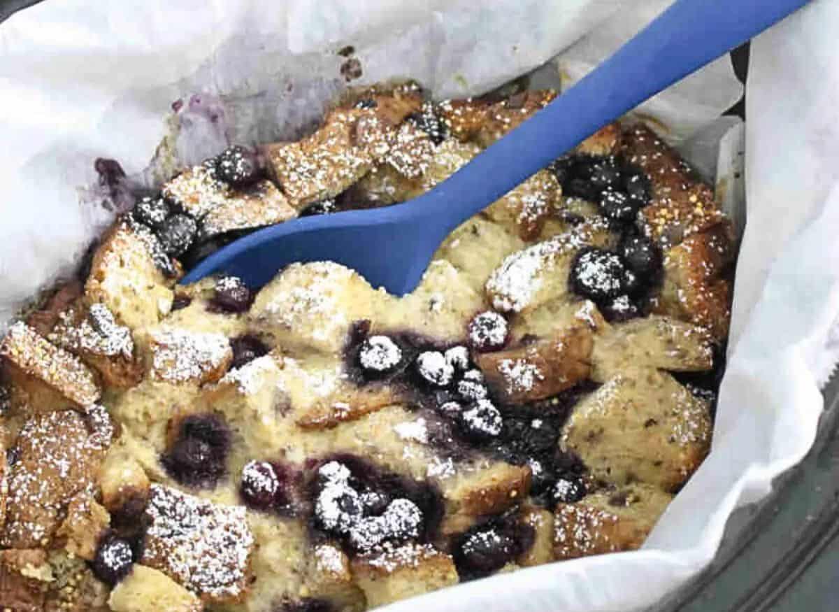 Slow cooker lined with parchment paper and filled with high protein French toast casserole with blueberries.
