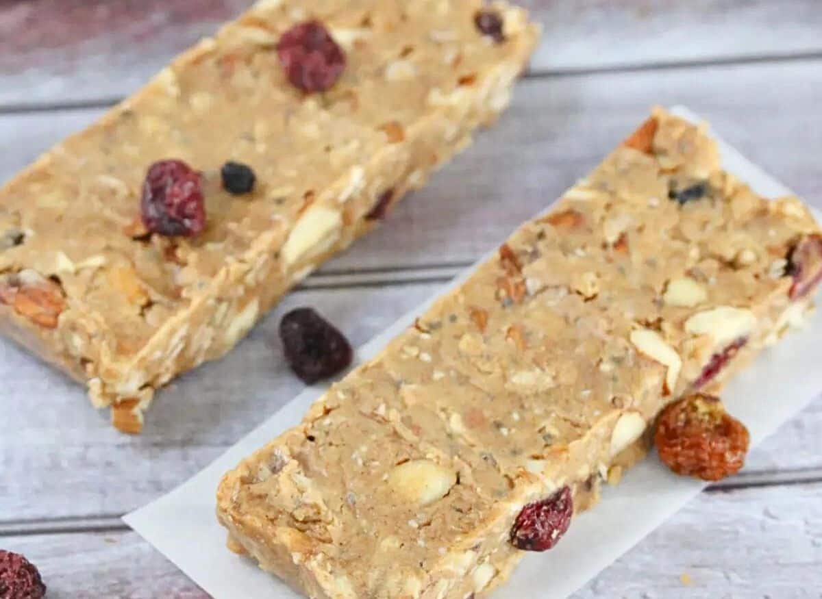 Homemade vegan protein bars in squares in front of protein powder in a scoop and more bars beside it.