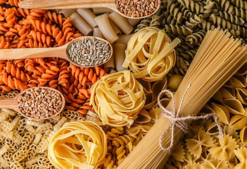 Various types of pasta and wooden spoons.