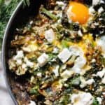 A skillet with eggs, spinach and pomegranate.