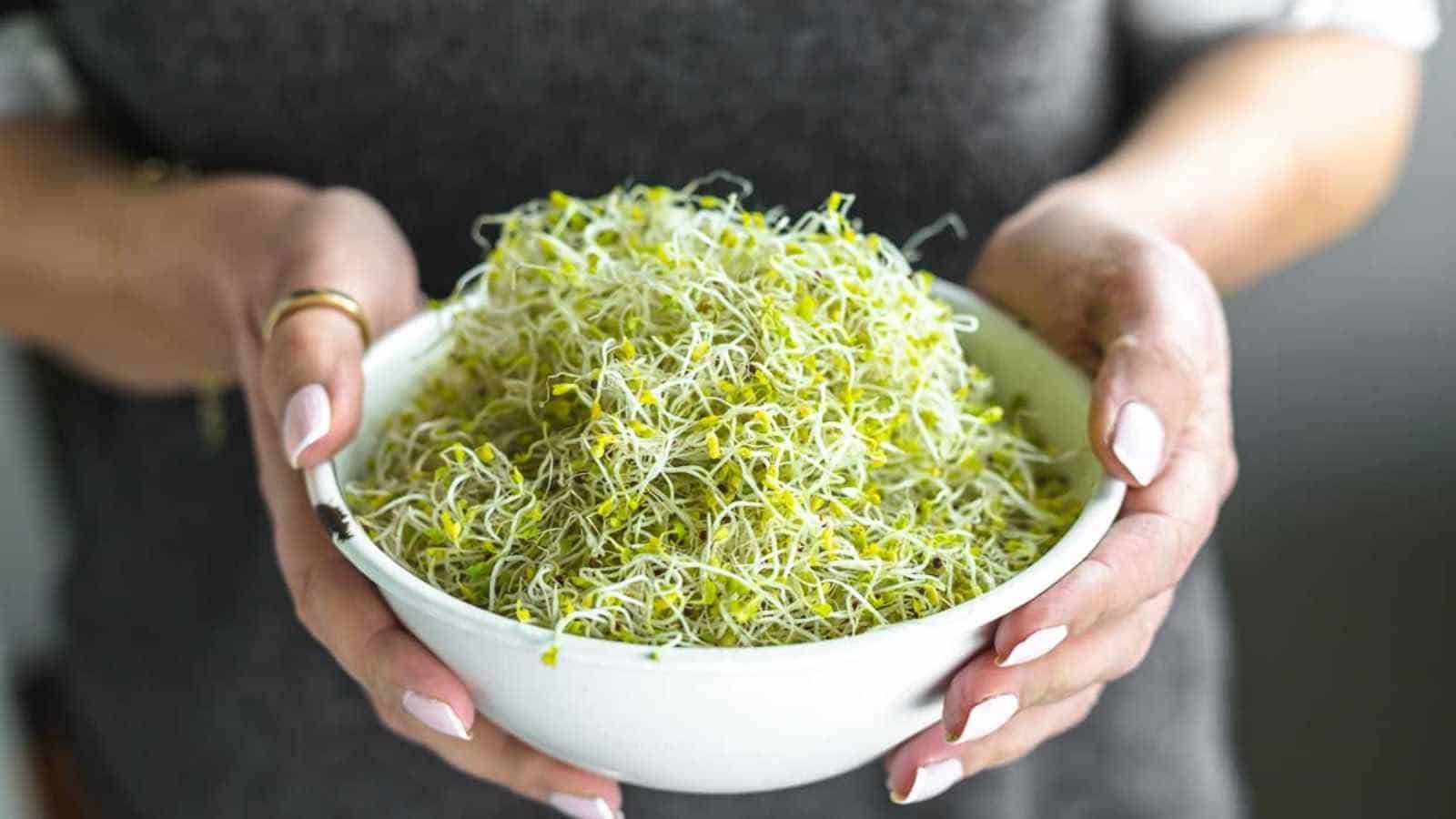 A woman holding a bowl full of broccoli sprouts.