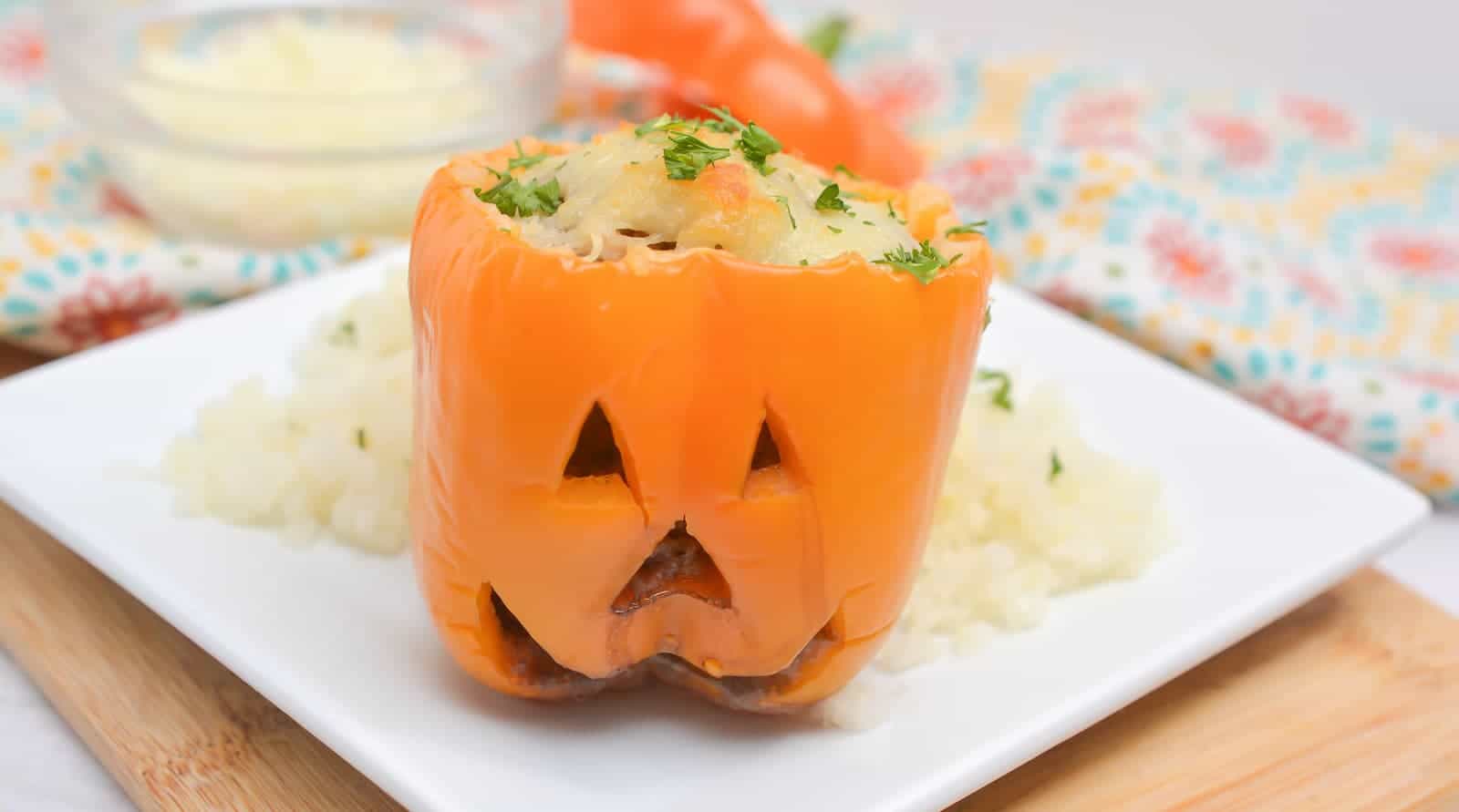 Halloween stuffed peppers with cheese on a white plate.