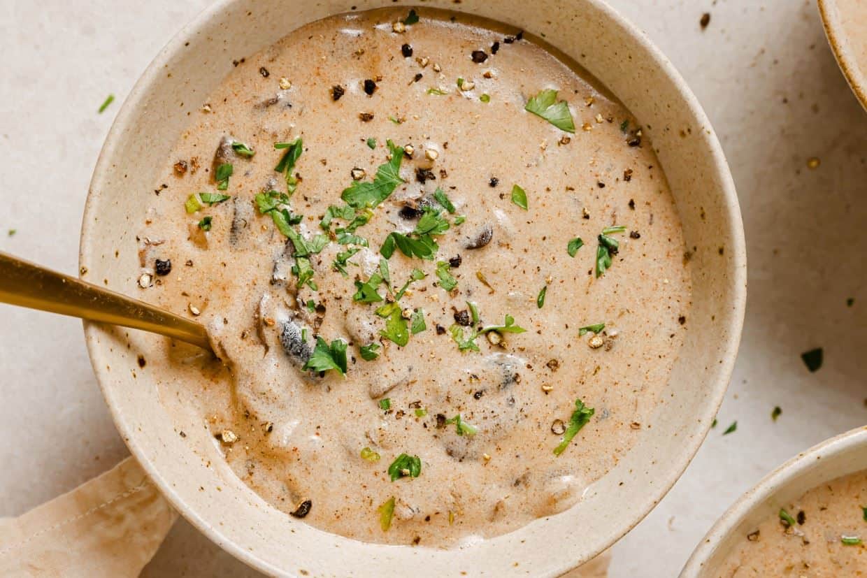 A bowl of Hungarian mushroom soup with a gold spoon.