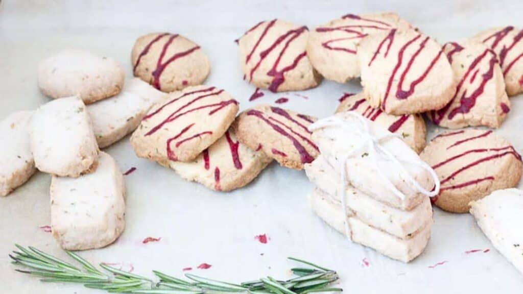 A tray of cookies with rosemary sprigs on it.