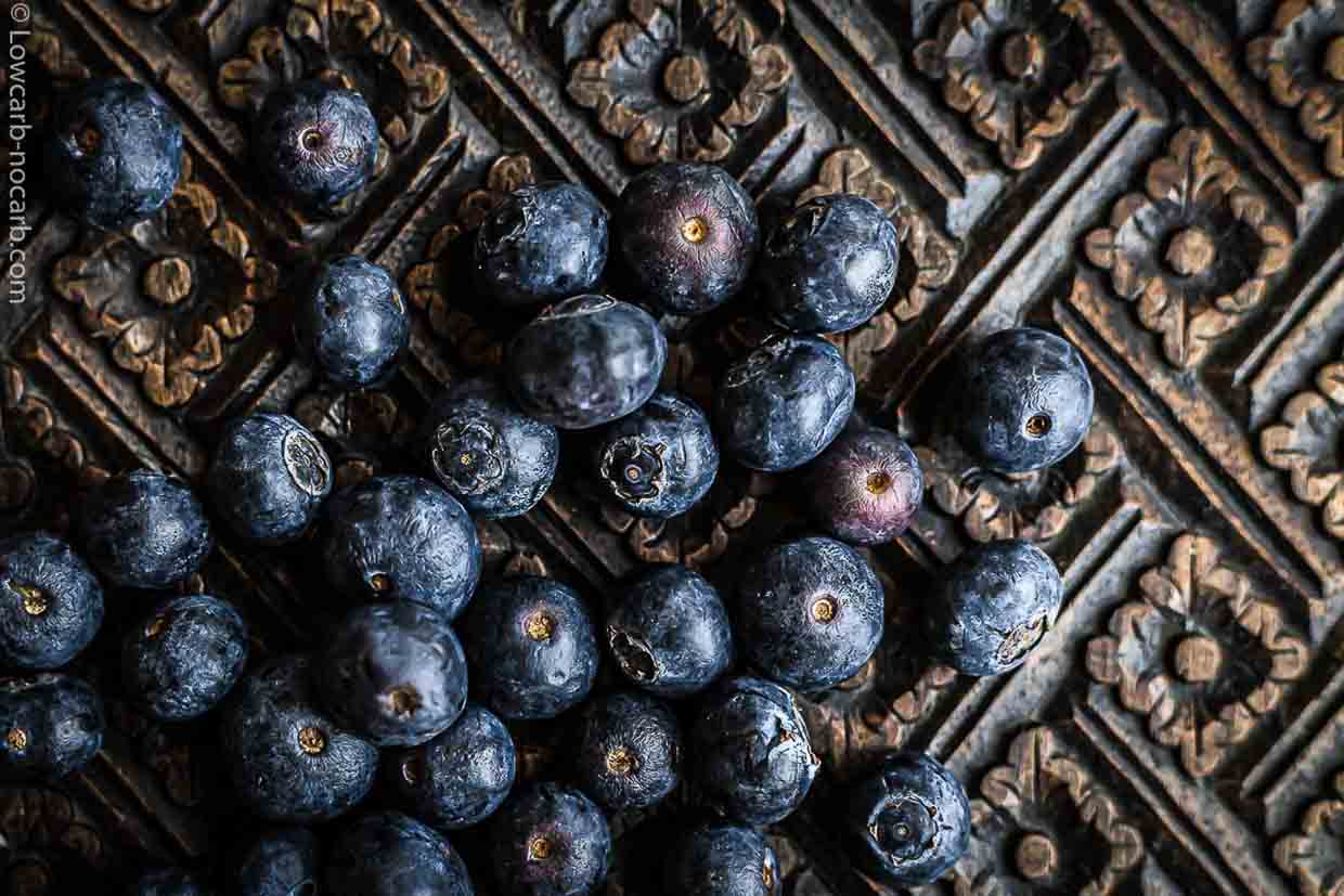 A close up of blueberries on a wooden surface.