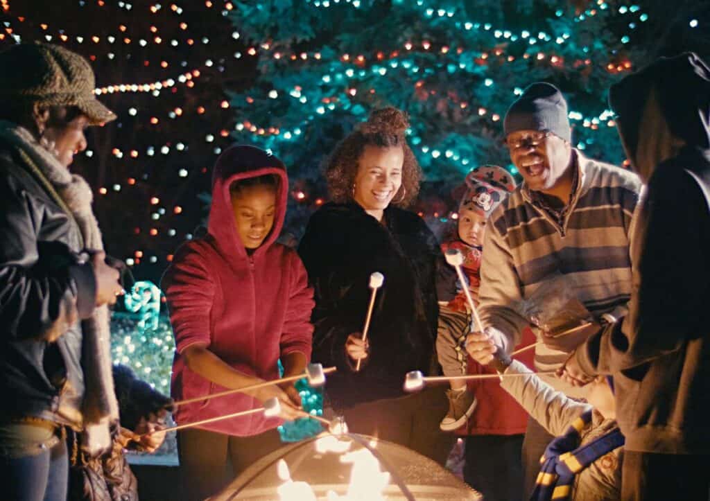 A group of people standing around a campfire roasting marshmallows at the Denver Zoo holiday event.