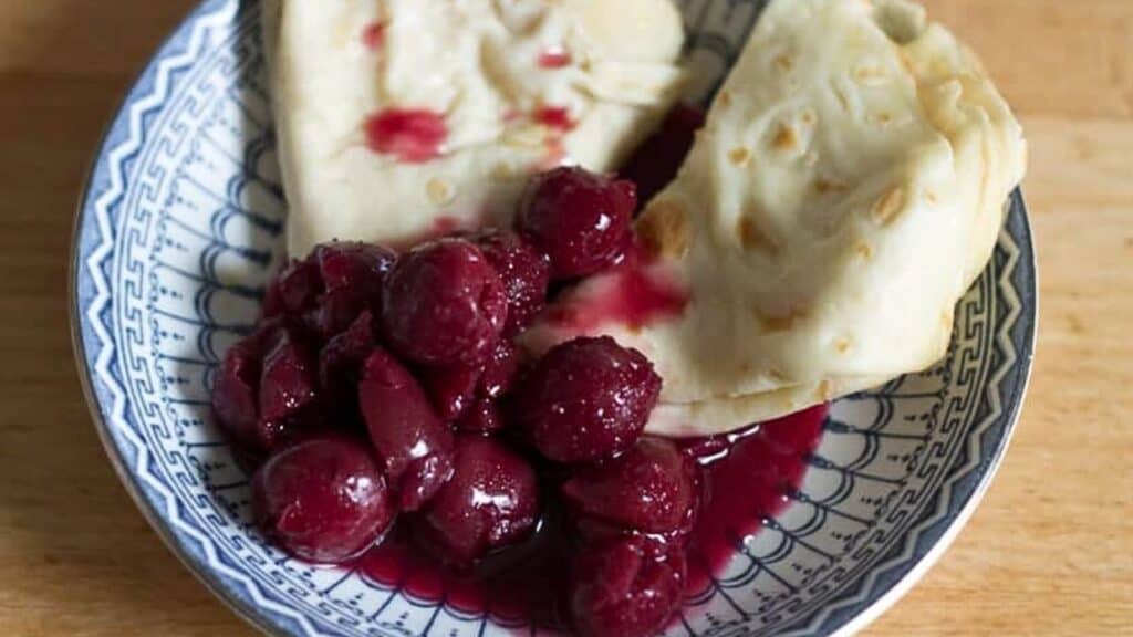 A plate with a bowl of fruit and a plate of bread.