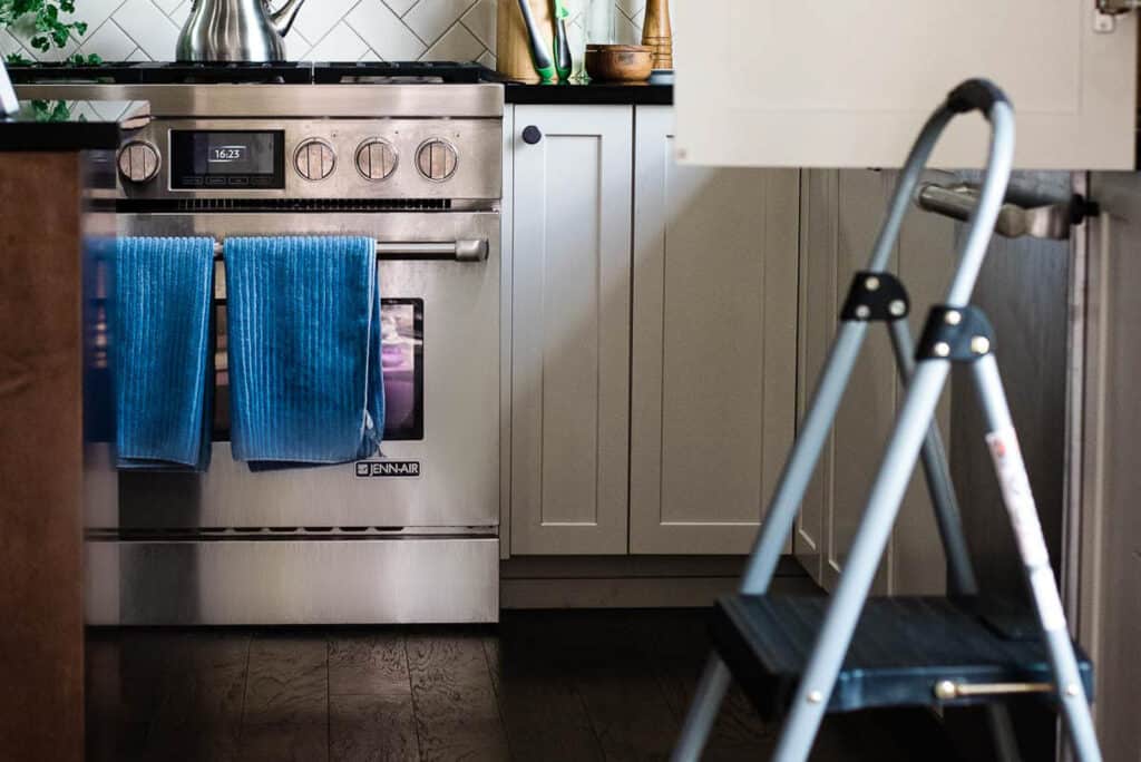 A kitchen with a stove and a ladder emphasizing kitchen safety.