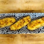 Three baked potatoes on a blue and white plate.