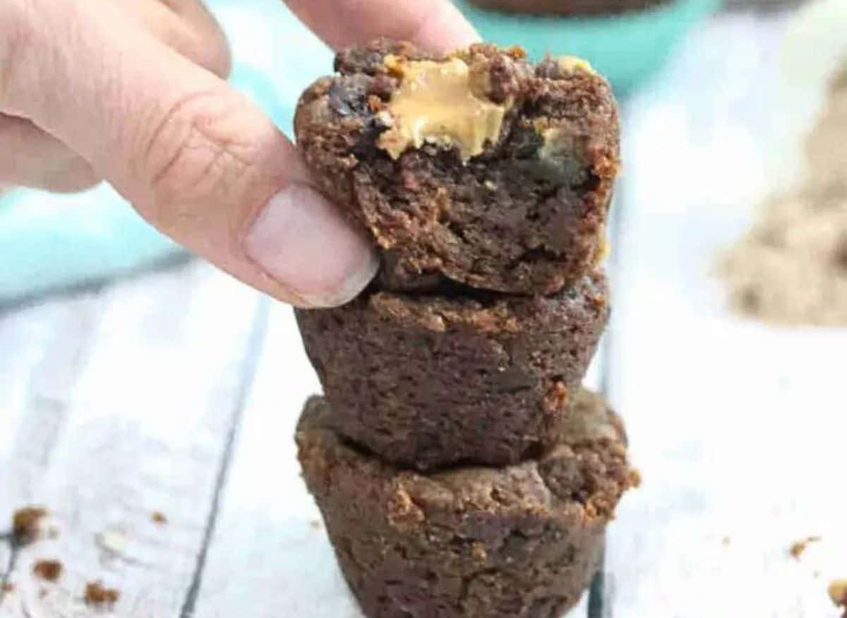 Three two-bite protein brownies stacked on top of each other with more in the background.