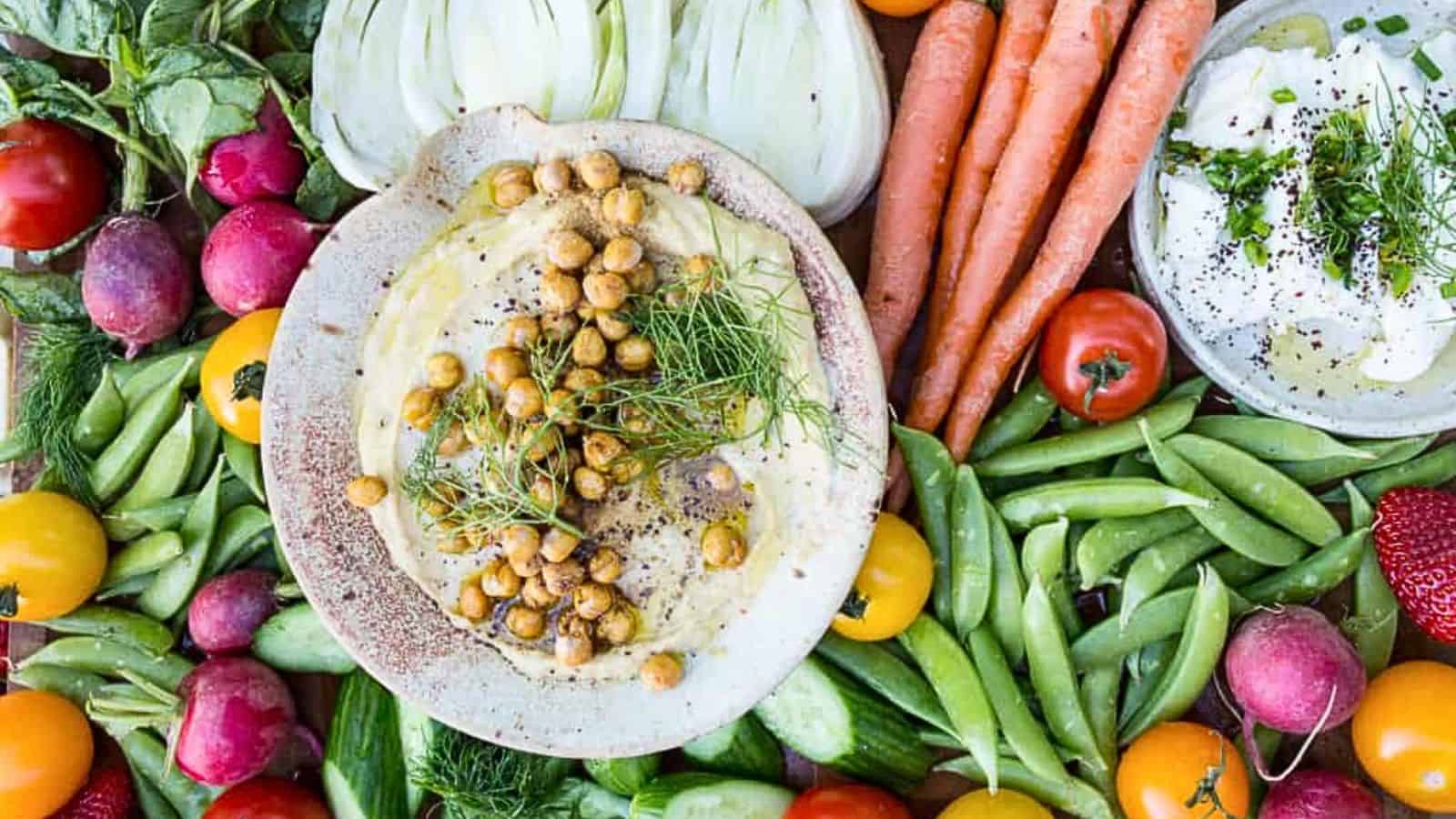 A plate full of vegetables and hummus.
