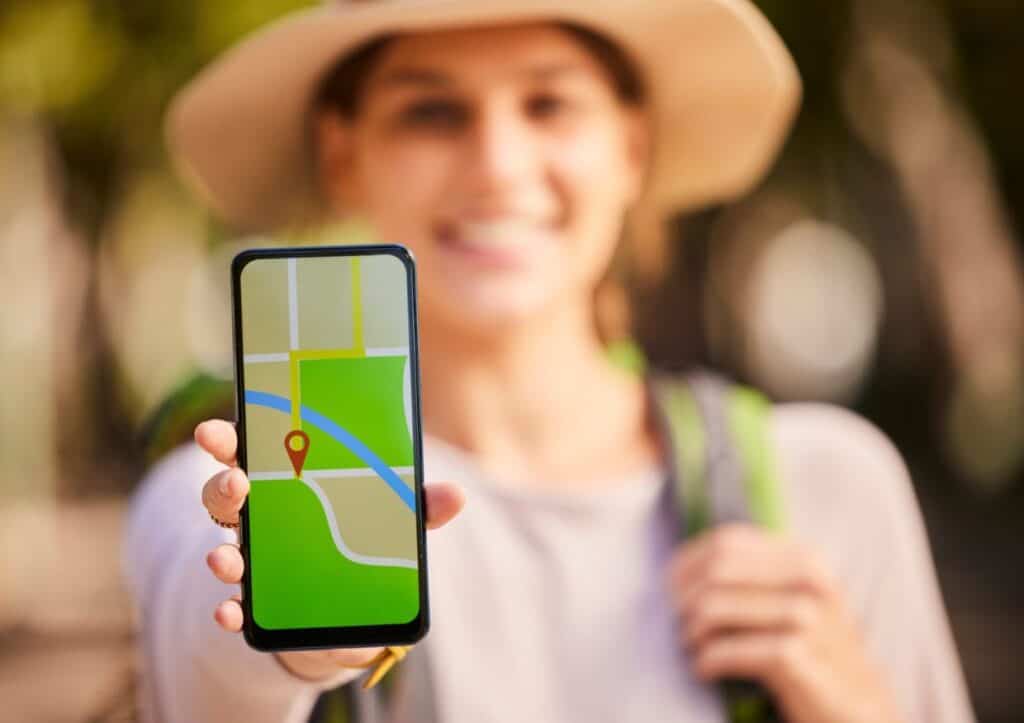 A woman participating in a scavenger hunt holds up a smartphone with a GPS map.