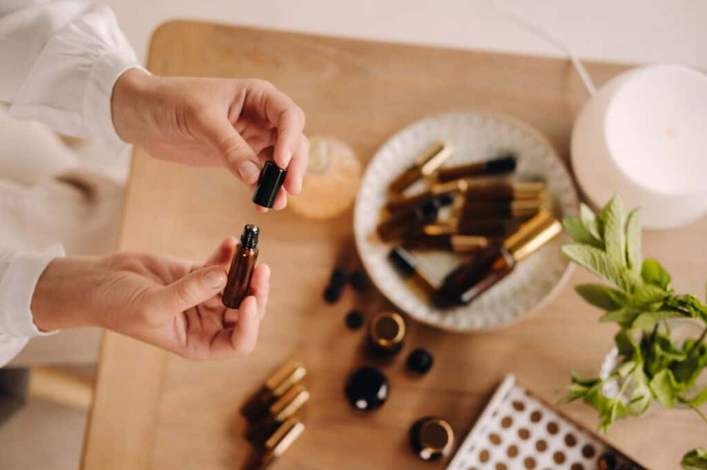 A woman opening a roller bottle of essential oils over a table.
