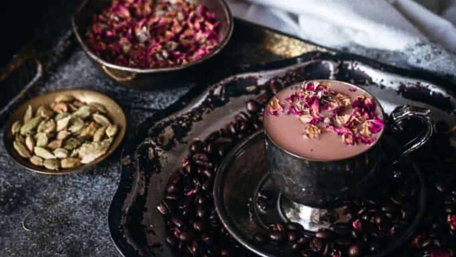 A cup of coffee with rose petals and pistachios.