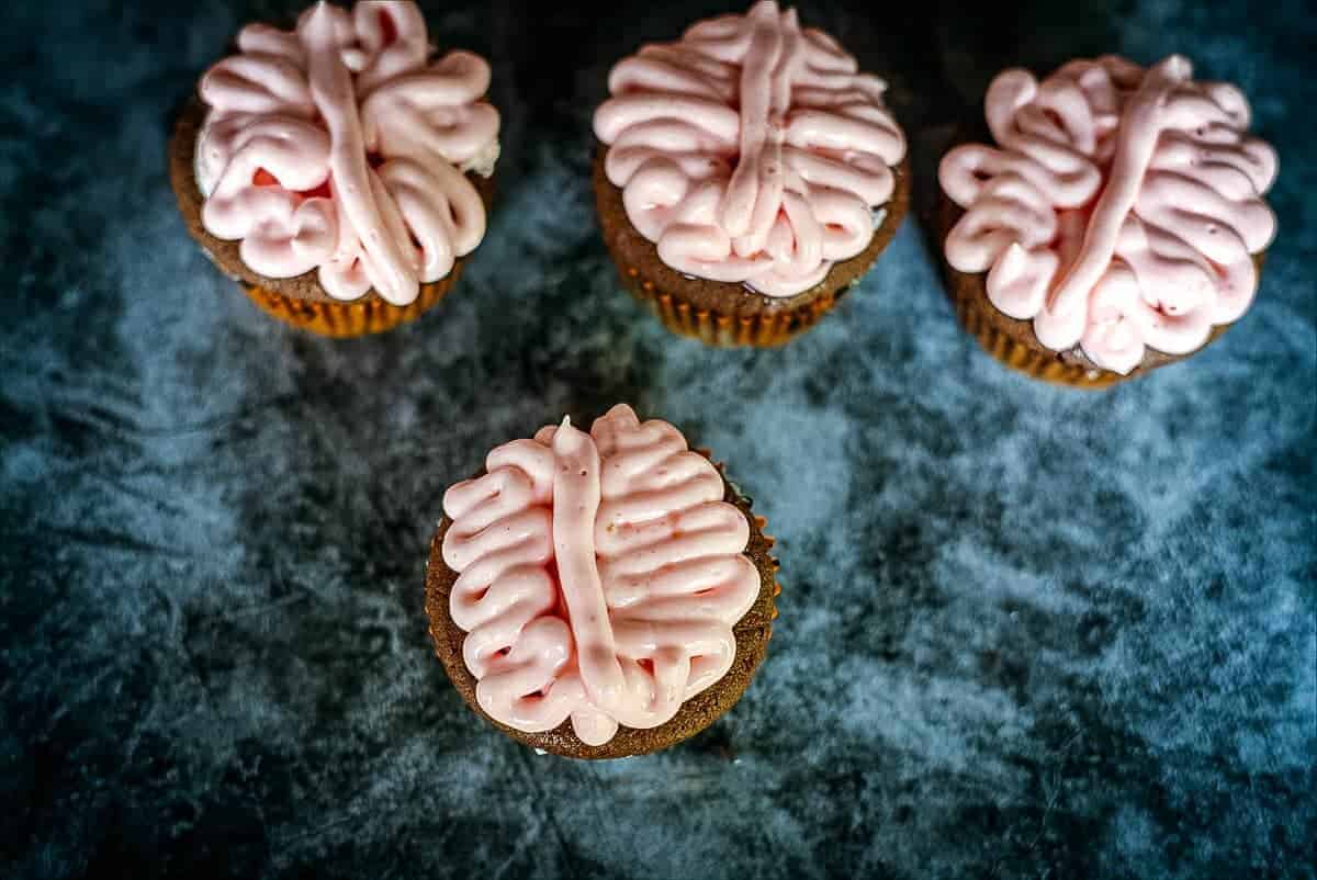 A group of brain cupcakes with a pink icing on them.