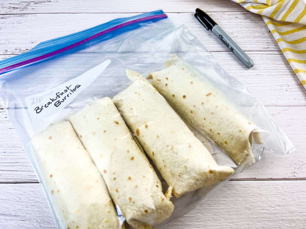 Freezer Breakfast Burritos in a plastic bag on a wooden table.