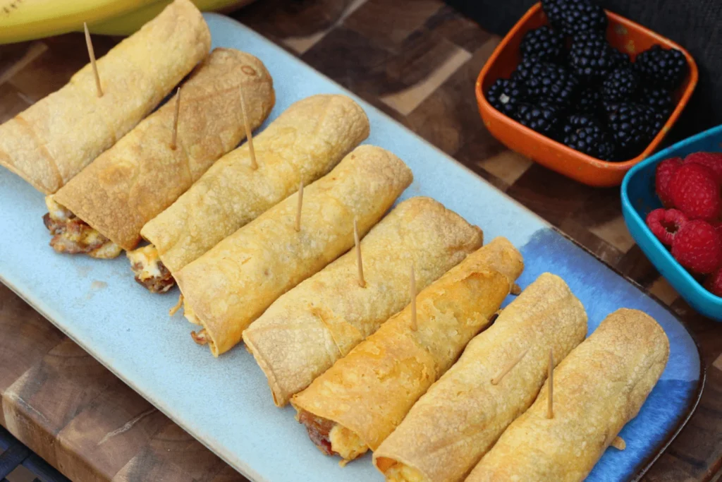 Breakfast burritos on a blue plate with berries.