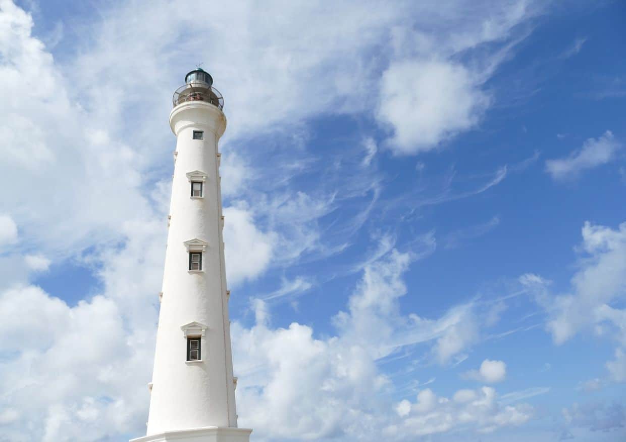 A white lighthouse with a blue sky in the background.