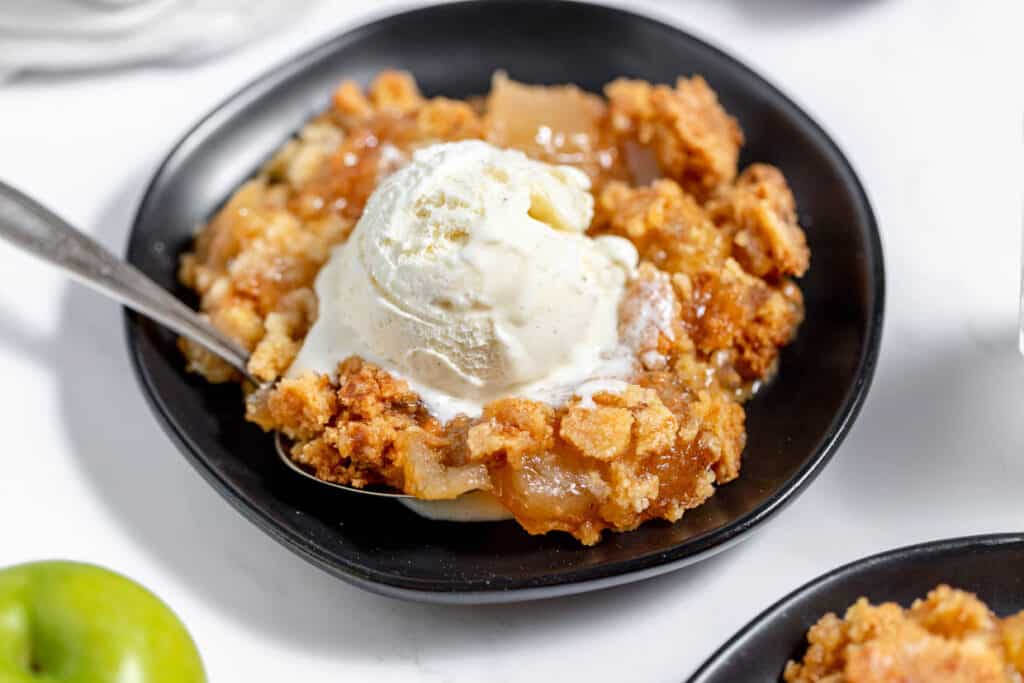 Apple crisp dessert made with cake mix, served in a bowl with ice cream.