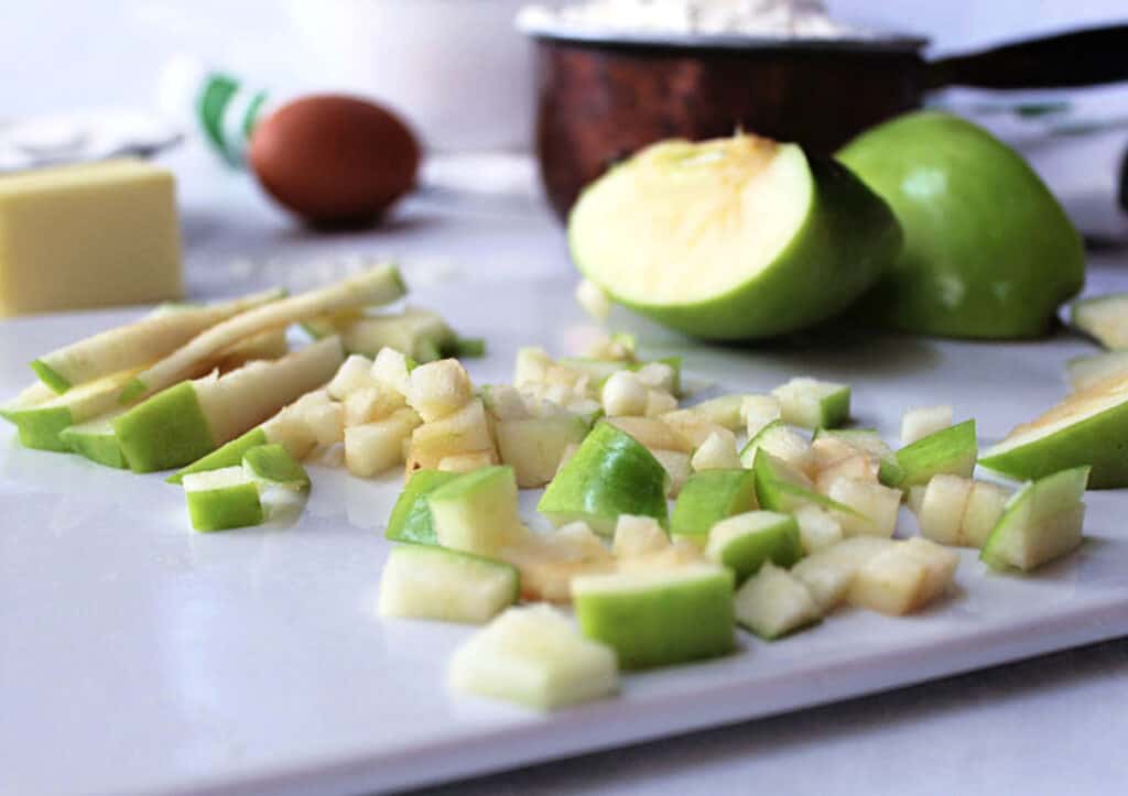 A white cutting board with diced apples.