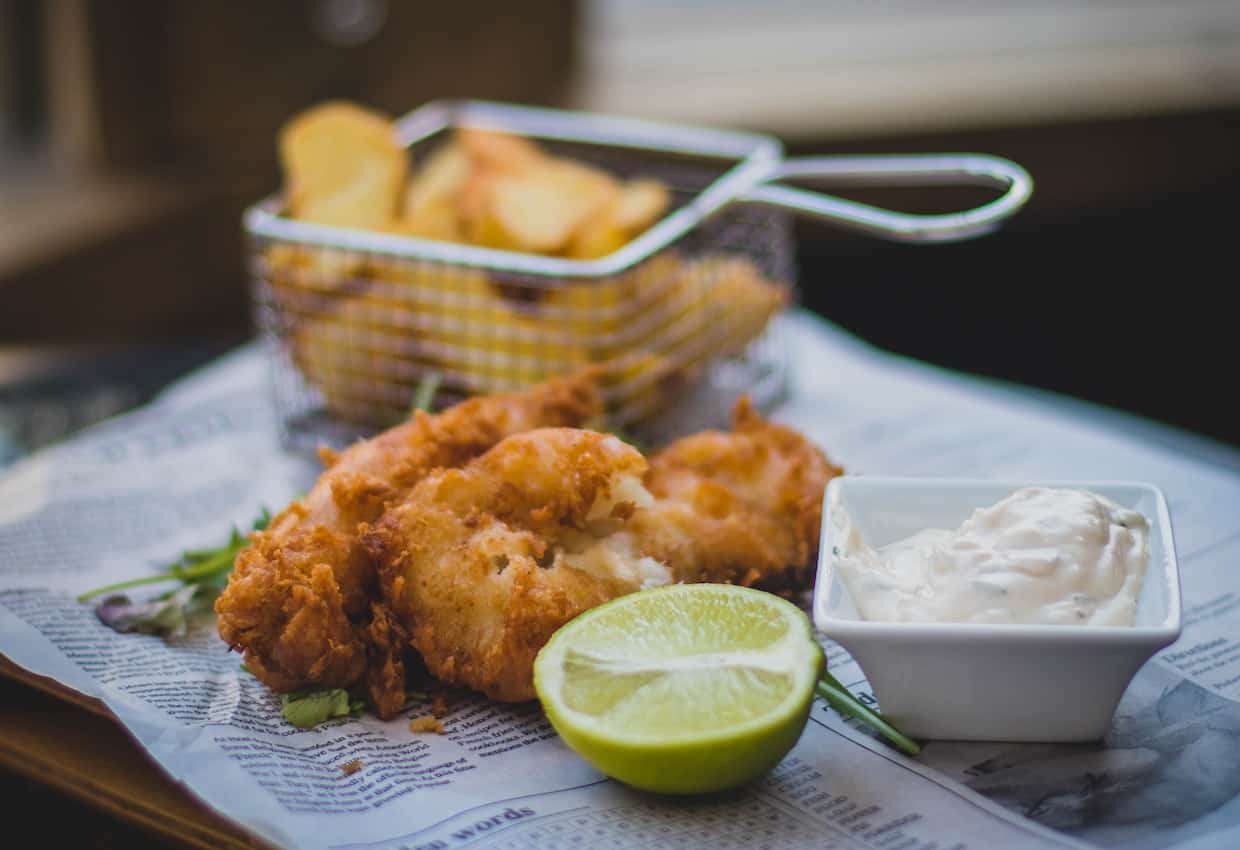 Fish and chips on a plate with a lime wedge.
