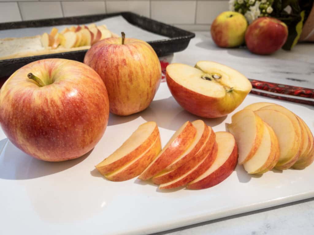 Sliced Gala apples on a white plate.