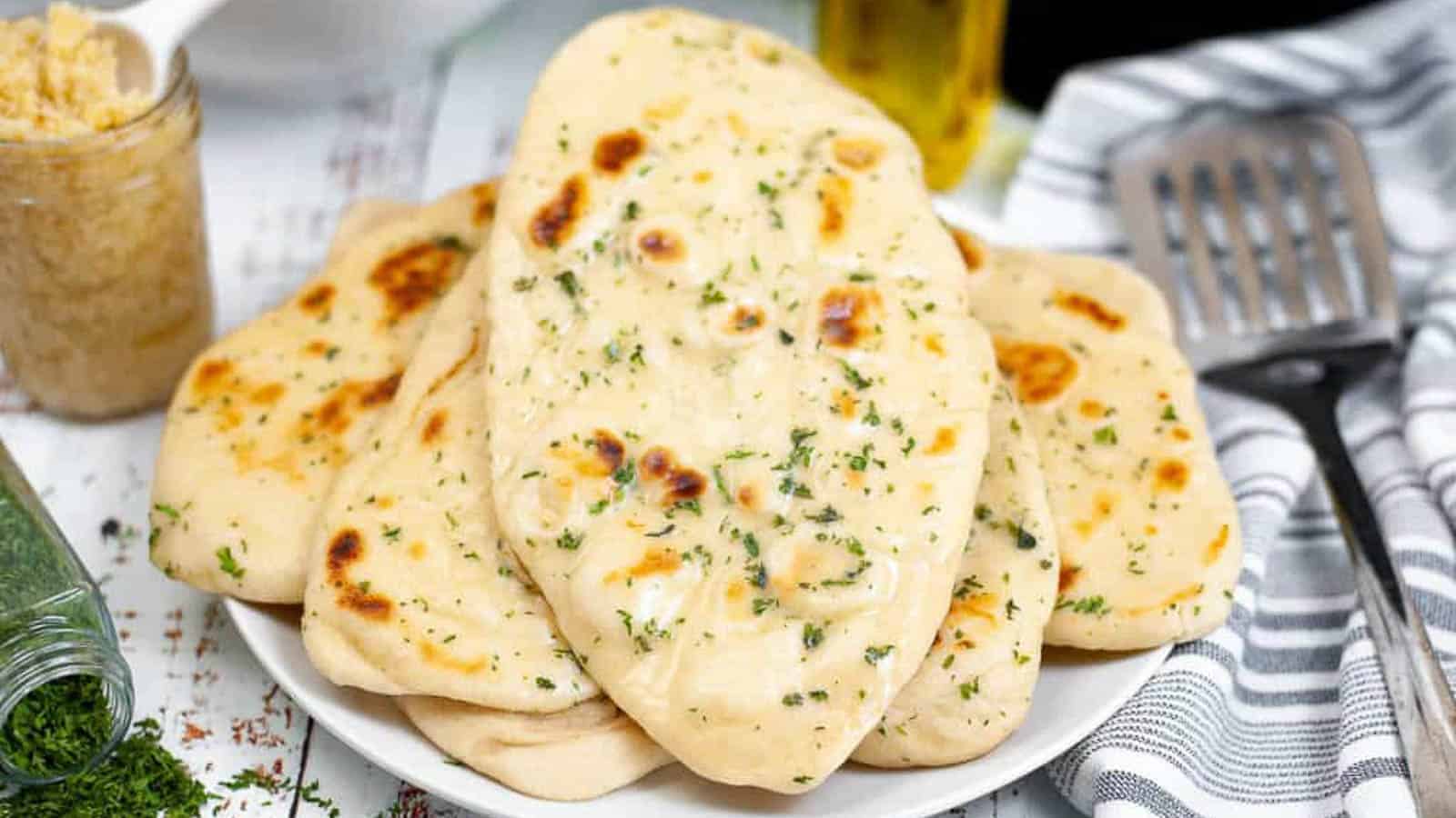 Low angle shot of a pile of garlic butter naan on a plate.