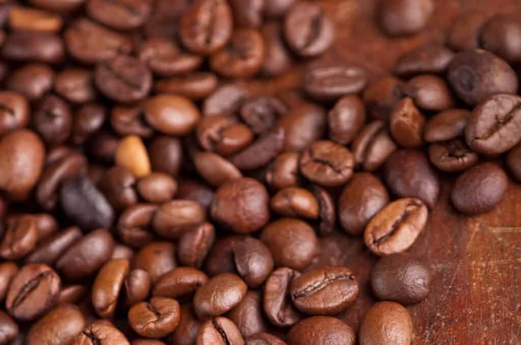 A close up of coffee beans on a wooden table.