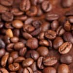 A close up of coffee beans on a wooden table.