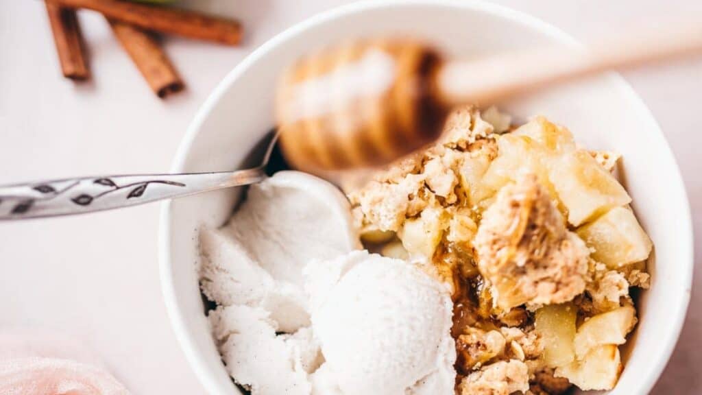 A bowl of apple crisp with ice cream and cinnamon.